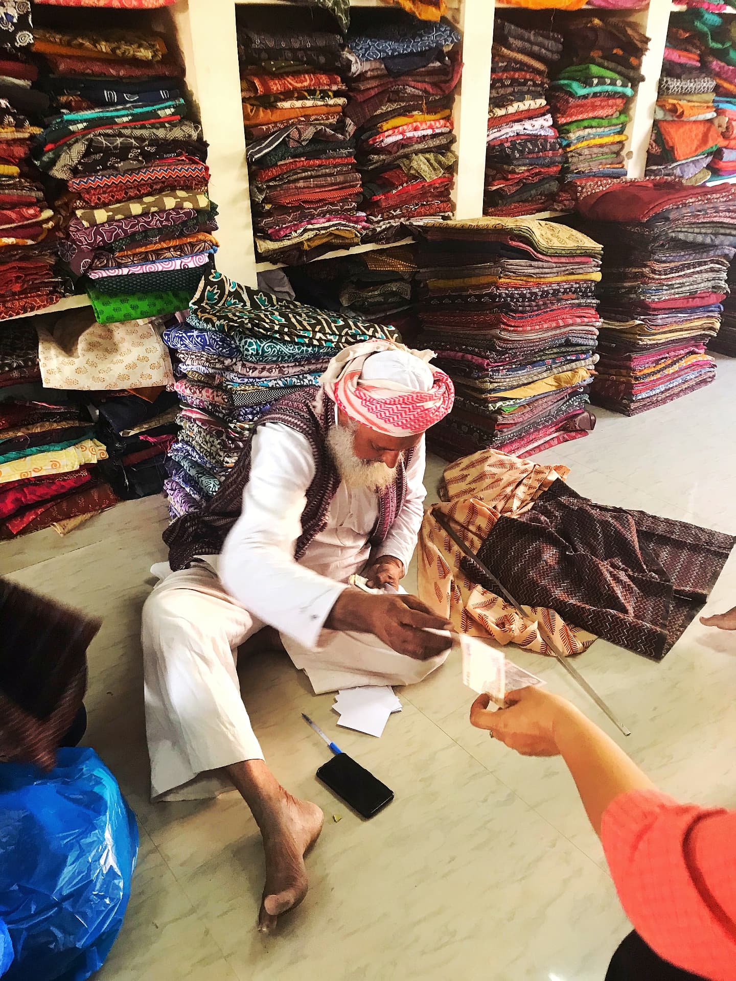 Textile artisan among stacks of hand block printed cloth